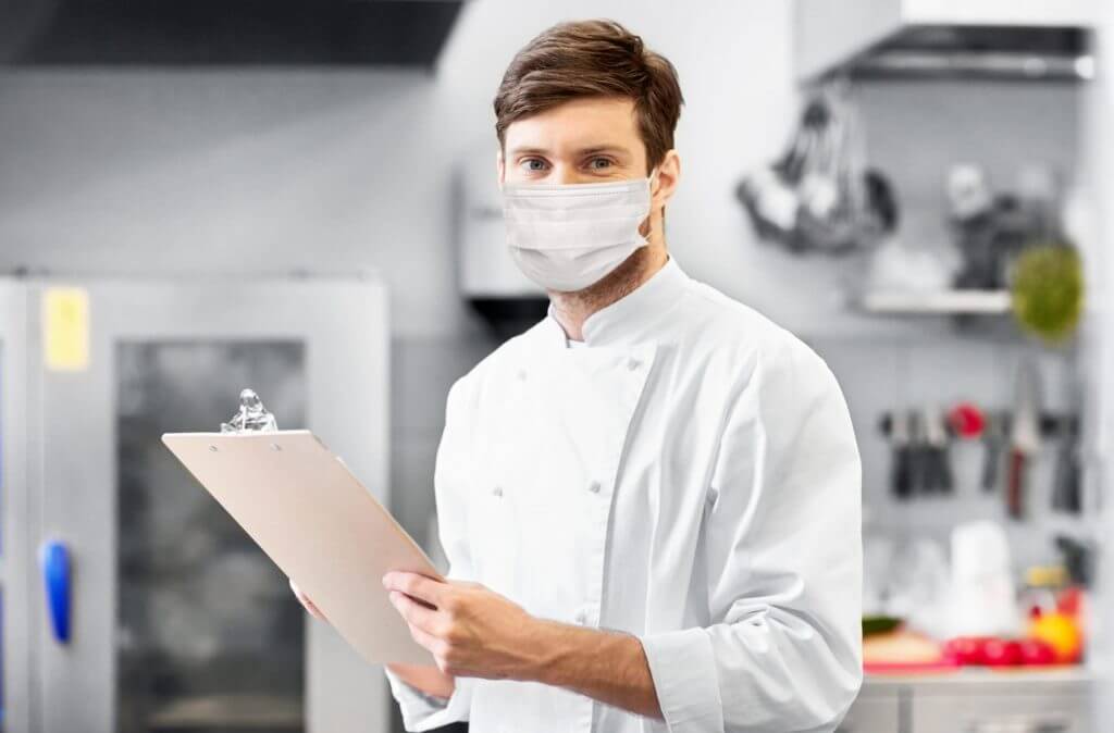 man with mask and clipboard in kitchen